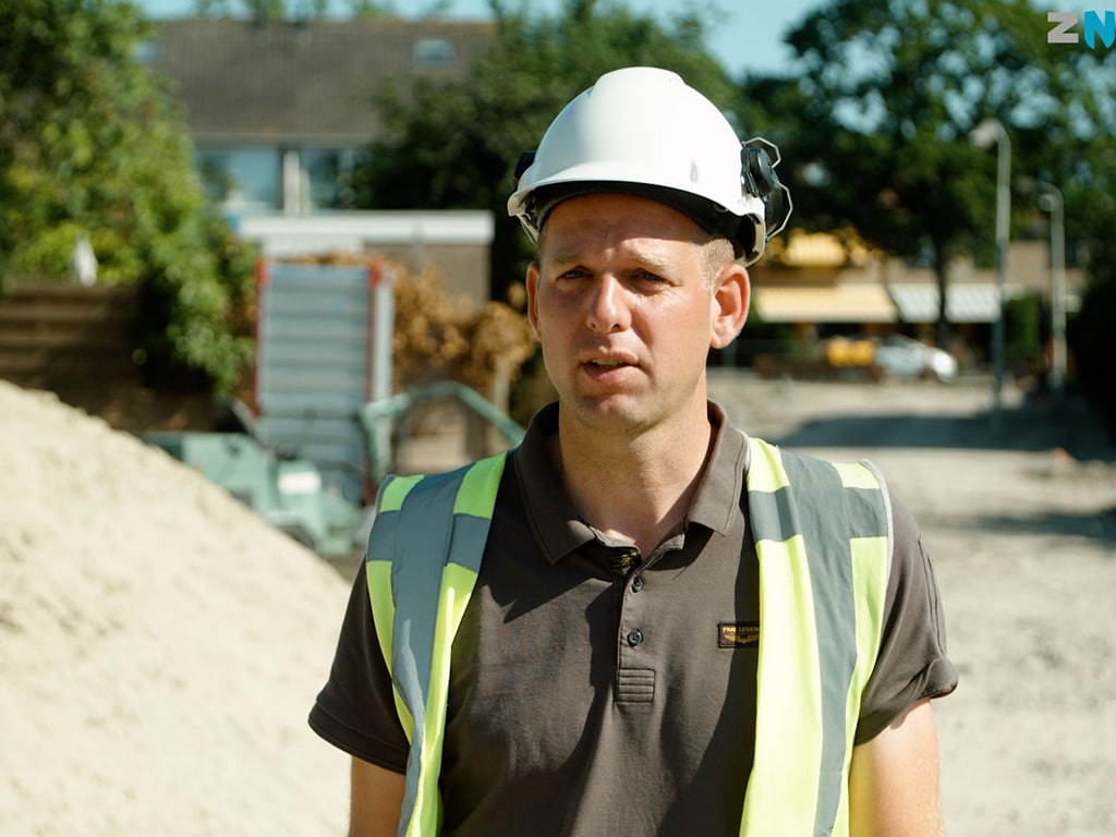 Medewerker Gemeente Zaanstad in veiligheidshelm en hesje geïnterviewd op bouwlocatie, employer branding video productie Mondha Media