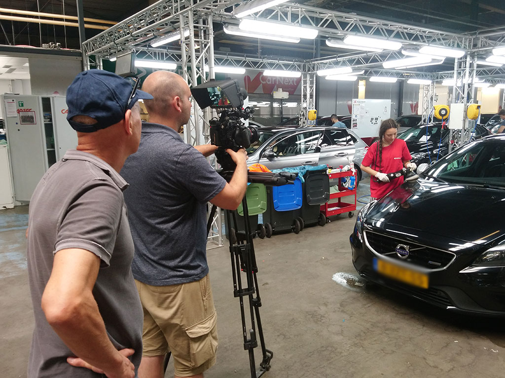 Cameraman van Mondha Media filmt een monteur die een auto polijst in de loods van Koopman Logistics, behind the scenes productiedag merkverhaal
