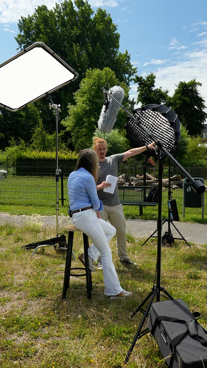 Cameraman van Mondha Media stelt lichtopstelling bij en bereidt een medewerker van Parnassia LIB voor op een interview buiten op het terrein, employee advocacy recruitment campagne