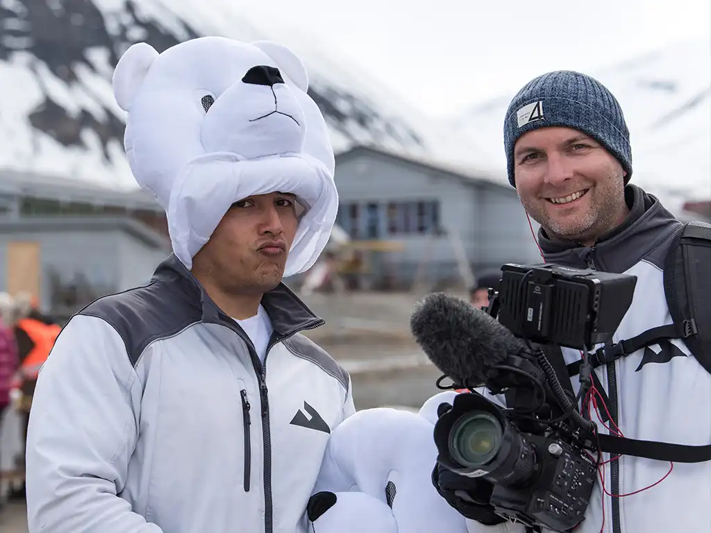 Aftermovie Arctic Marathon — Mondha Media achter de camera Cameraman van Mondha Media filmt de aftermovie van de Arctic Marathon met een organisatielid met ijsbeermuts in besneeuwd Spitsbergen