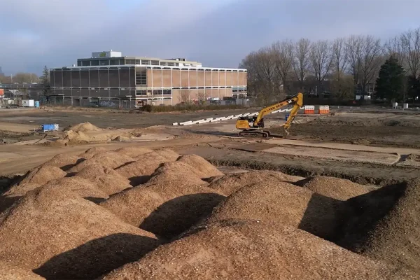 Bouwterrein met graafmachine en zandhopen waar een project van gemeente Utrecht wordt gerealiseerd