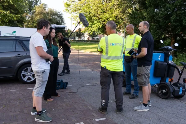 Filmcrew en buitendienstmedewerkers van gemeente Zaanstad overleggen op locatie voor de volgende opname