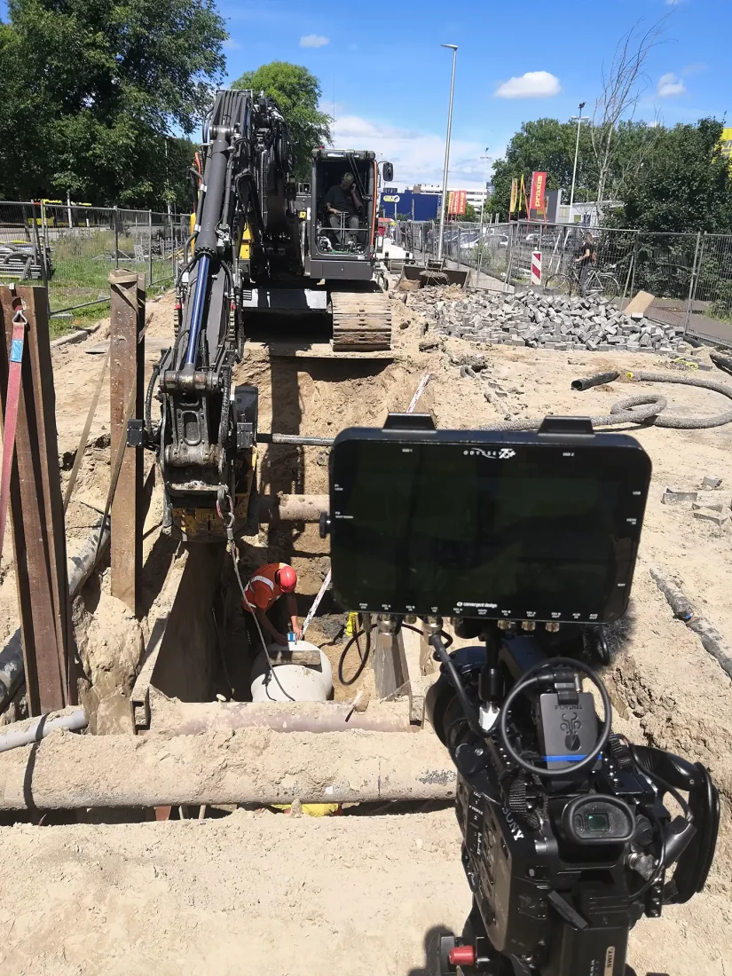Behind the scenes graafwerk – wervingsvideo techniek gemeente Utrecht Camera met monitor filmt een graafmachine en een grondwerker in een sleuf tijdens de opname van de wervingsvideo techniek voor gemeente Utrecht