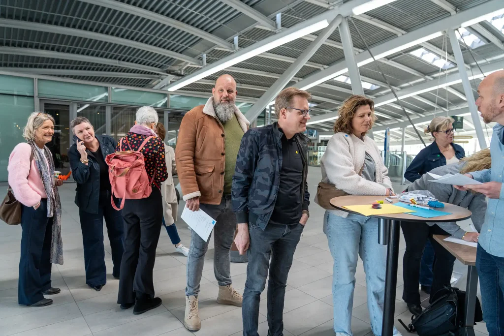 Groep deelnemers bij de ontvangst van de bijeenkomst in een lichte stationshal, fotografie bij de promotiefilm van Humanitas DMH