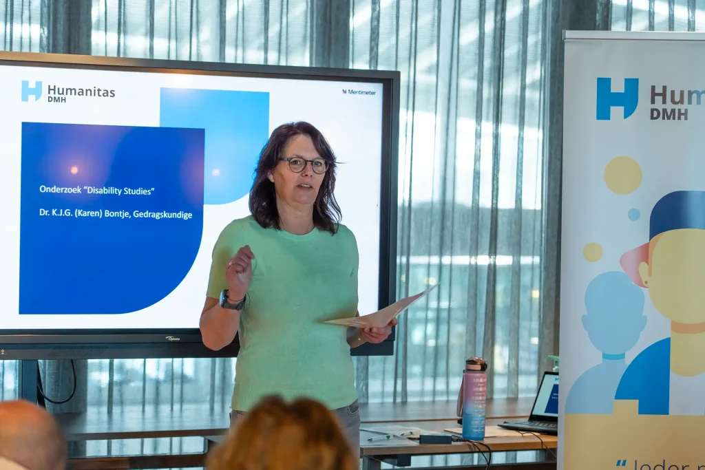 Spreker presenteert het onderzoek Disability Studies voor het scherm van Humanitas DMH, fotografie bij de promotiefilm van Humanitas DMH