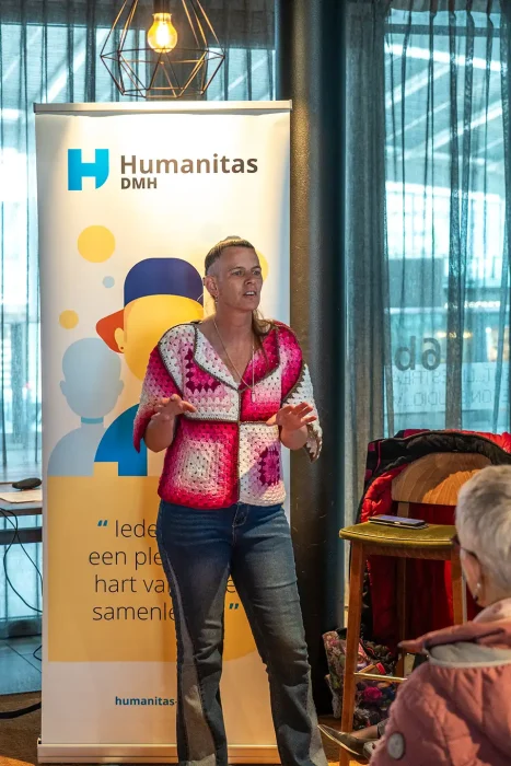 Ervaringsdeskundige vertelt staand haar verhaal voor de Humanitas DMH-banner, fotografie bij de promotiefilm van Humanitas DMH