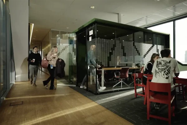 Medewerkers lopen en overleggen in het moderne kantoor van gemeente Utrecht in een wervingsvideo over inkoop
