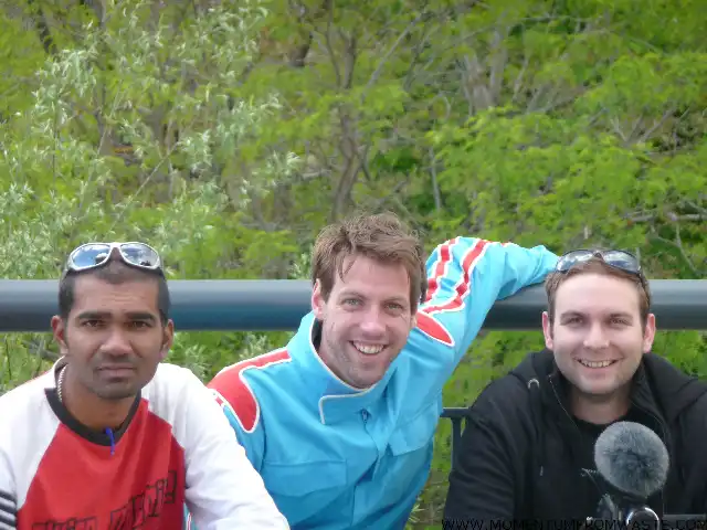 Sebastiaan Justin Avinash tijdens de wonders of waste rally 2010 Drie glimlachende mannen van het Mondha Media team poseren buiten voor een groene, bosrijke achtergrond leunend tegen een reling