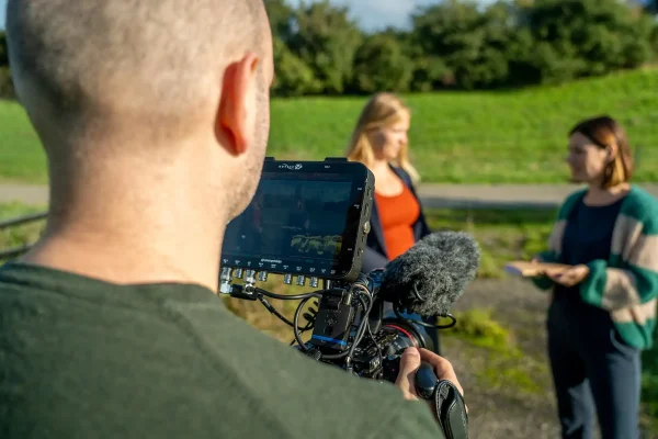 InterviewopnaInterview opname wervingsvideo Utrecht Energie Cameraman van Mondha Media filmt een interview met twee vrouwen in een groen weiland tijdens de videoproductie voor Utrecht Energie