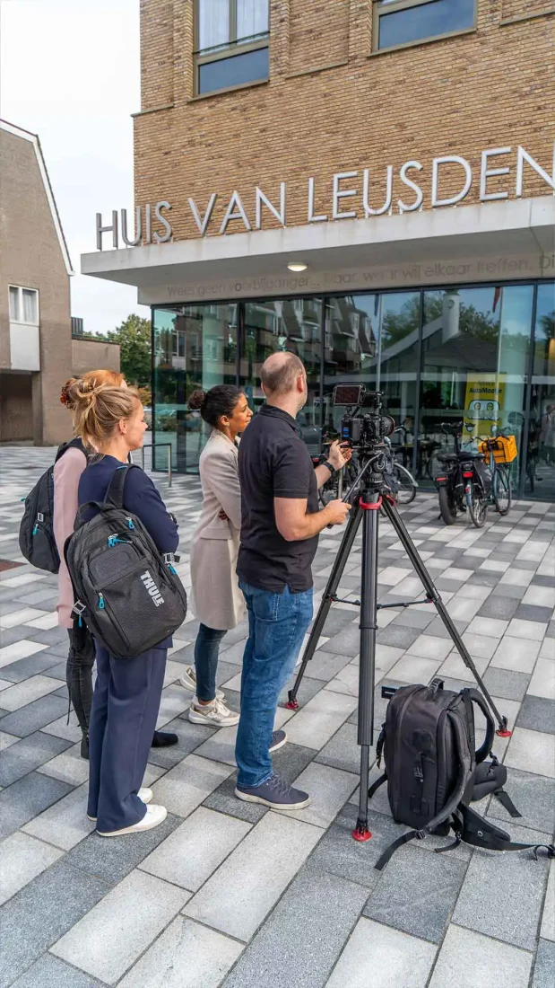 Opnames bij het Huis van Leusden Een staande foto van een cameraploeg en medewerkers bij de ingang van het Huis van Leusden tijdens opnames voor de gemeentelijke wervingscampagne.