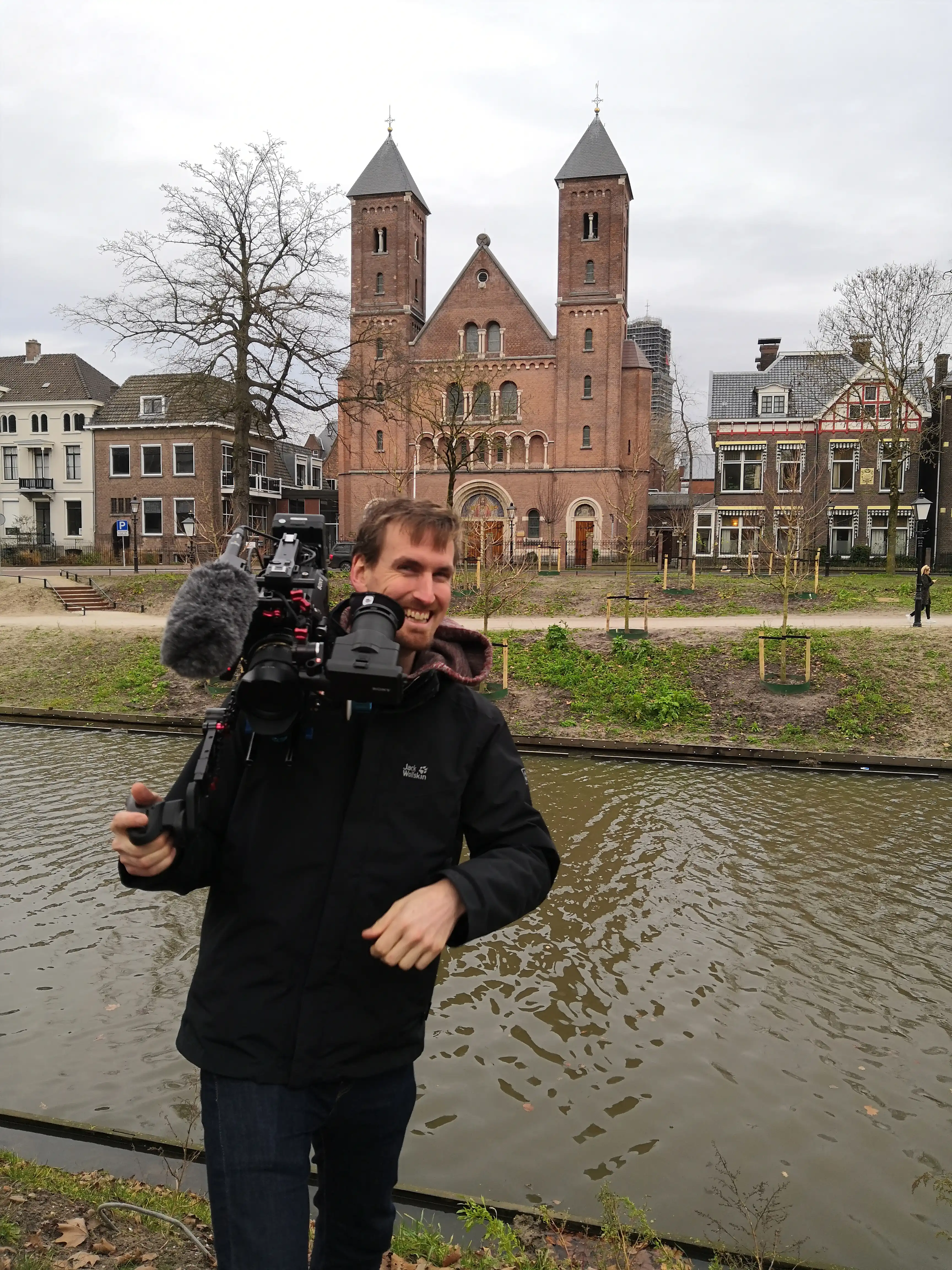 Werken bij gemeente Utrecht — cameraman Ben aan het werk Cameraman Ben van Mondha Media filmt aan de Utrechtse singel voor de video over werken bij gemeente Utrecht, met een historische kerk op de achtergrond