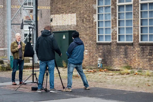 Cameraman Ben en regisseur Sebastiaan van Mondha Media filmen een medewerker van gemeente Zaanstad voor een industrieel bakstenen gebouw