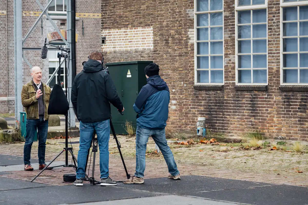 Cameraman Ben en regisseur Sebastiaan van Mondha Media filmen een medewerker van gemeente Zaanstad voor een industrieel bakstenen gebouw