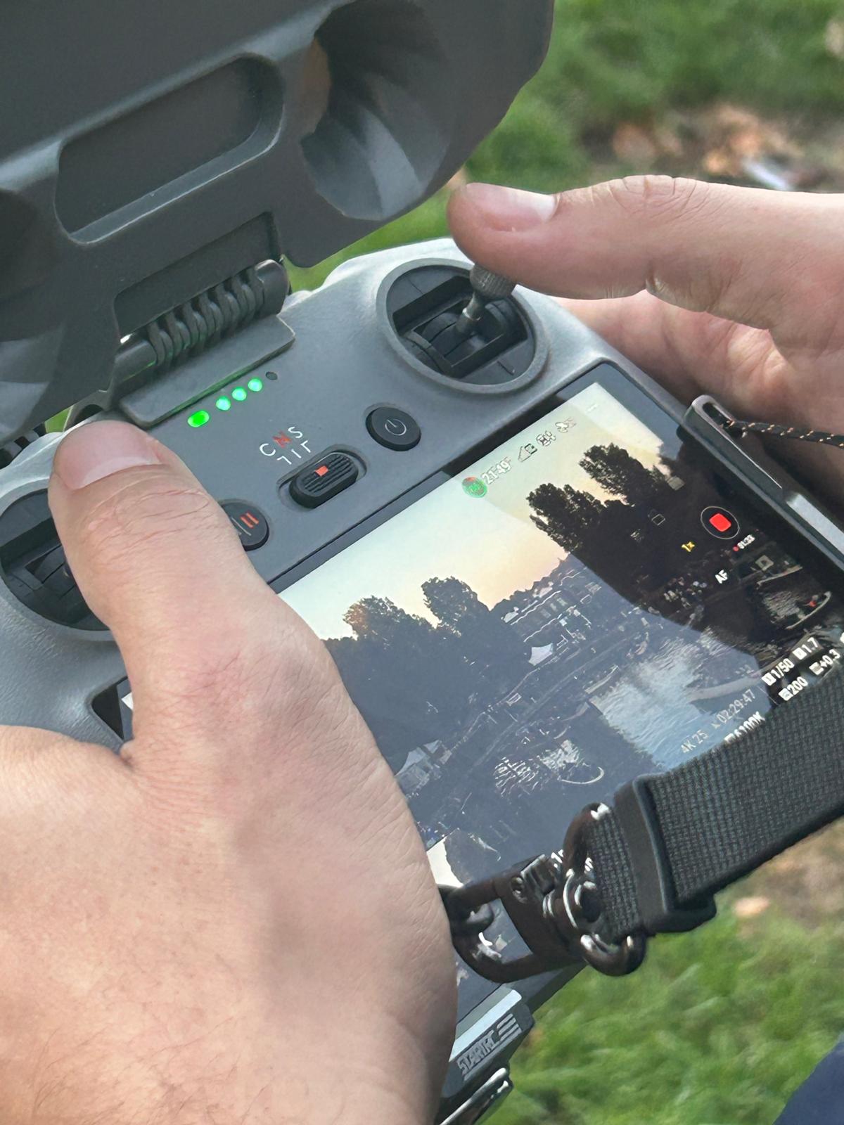 Dronebeelden Harlingen Ongeschut: achter de schermen bij de VVNL-portretvideo Dronecontroller met livebeeld van een gracht met boten bij zonsondergang tijdens het filmen van Harlingen Ongeschut voor VVNL